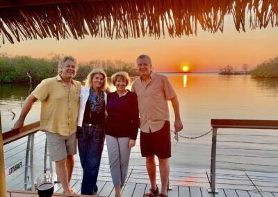 Guests taking photos on a tiki boat at golden hour